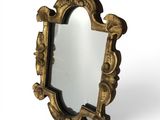 un miroir doré richement décoré, avec un cadre noir et un fond blanc