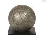 a metal ball on a wooden base on a white background