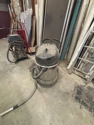 une photo d'une pièce où l'on voit un aspirateur et d'autres objets posés par terre