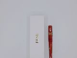 a red pen sitting on top of a white box next to a red pen