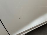 a close up of a white car with a hole in the door