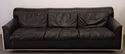 a black leather couch sitting in a corner of a room
