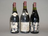 trois bouteilles de vin sont posées sur une table devant un fond blanc