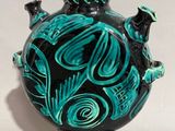a black and green vase sitting on a white surface
