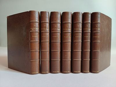 six livres en cuir marron alignés sur une surface blanche