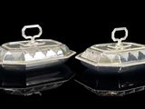 pair of silverplated butter dishes with lids on a black surface