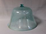 une cloche en verre avec un haut vert sur fond blanc