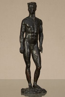 statue en bronze représentant un homme debout sur un rocher, les mains dans les poches