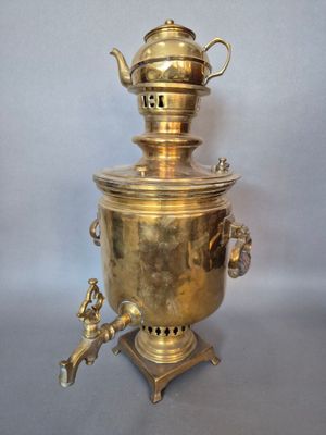 une bouilloire à thé en laiton ancien posée sur un support, sur fond blanc