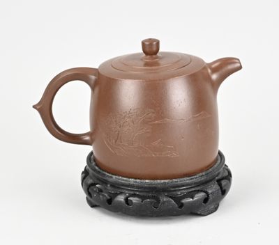 une théière marron posée sur un socle noir