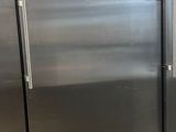three stainless steel refrigerators in a kitchen with a table
