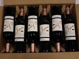six bottles of wine in a cardboard box on a table
