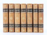 six vieux livres sont alignés sur une surface blanche