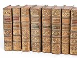 several old books are lined up in a row on a white surface