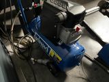 a blue air compressor sitting on the floor in a garage