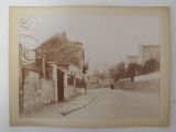 an old photo of a person walking down a street in an old town