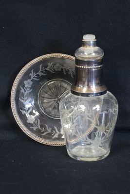 une bouteille en verre avec un bouchon argenté, posée à côté d'une assiette en verre