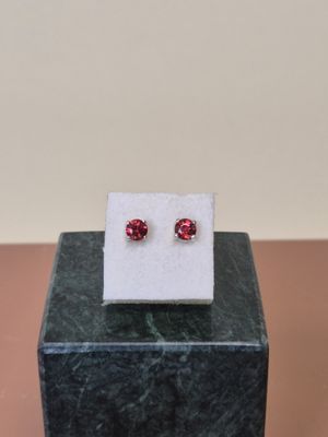 a pair of red cubicge earrings sitting on top of a marble block