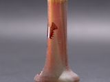 a small vase with a bird on it on a table
