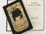 an old book with a gold cover sitting on top of a white table