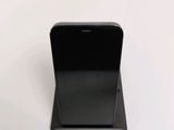 a black cell phone on a stand on a white surface