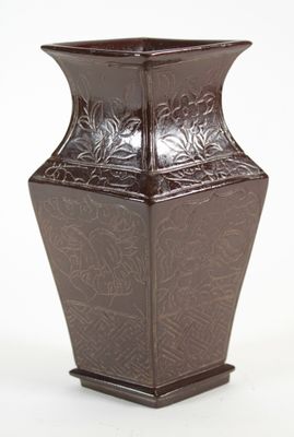 un vase marron posé sur une surface blanche