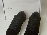 black sued sneakers with white soles and laces in front of a white box
