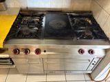 une cuisinière en acier inoxydable à quatre feux et une serviette jaune posée sur le plan de travail