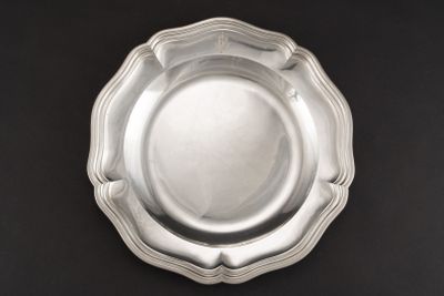 une assiette en argent posée sur une table noire, sur fond noir