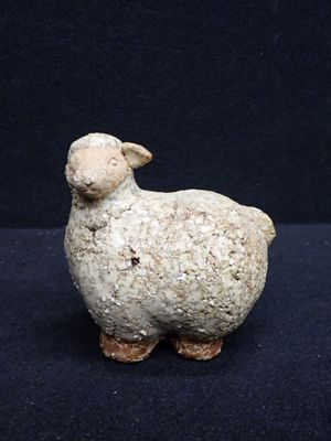 une petite statue représentant un mouton posée sur une surface noire