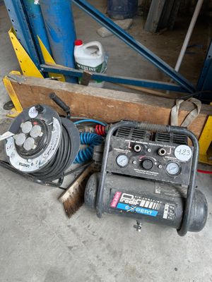 a small air compressor sitting on the floor next to a pile of tools