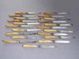 Plusieurs couteaux sont alignés sur une surface grise