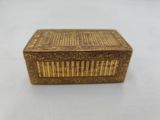 une petite boîte en or avec un couvercle en bois, posée sur une surface blanche