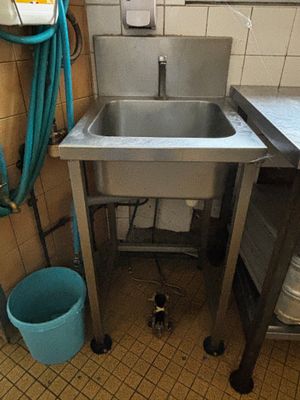 un évier dans un coin de la cuisine, avec un seau bleu