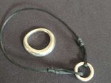 une bague en argent montée sur un cordon noir, sur laquelle est fixée une autre bague en argent