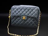 a black chanel bag with gold chain on a black background
