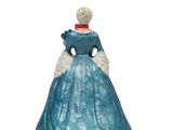 the figurine of a woman in a blue dress is standing on a white surface