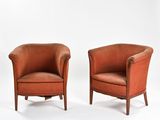 une paire de fauteuils club en cuir orange, avec des pieds et des accoudoirs en bois