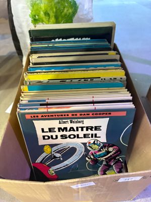 une boîte remplie de livres posée sur une table, avec une plante en arrière-plan