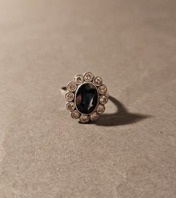 une image représentant une bague ornée d'une pierre noire entourée de diamants blancs