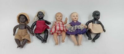 five black dolls are lined up in a row on a white surface