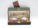 two silver spoons in a green box on a white surface