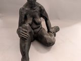 statue représentant un garçon assis par terre, les mains posées sur les genoux