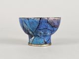 un bol bleu posé sur une table, sur fond blanc
