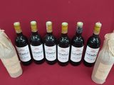 six bottles of wine are lined up in a row on a red table