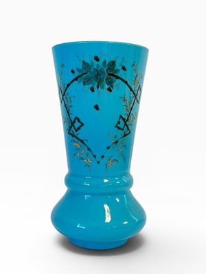 vase en verre bleu orné d'un motif floral sur fond blanc