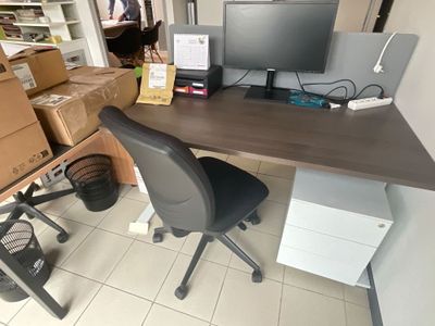 un bureau sur lequel se trouve un ordinateur, avec une chaise devant