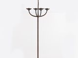 un lampadaire en métal avec trois bougies posées sur un socle, sur fond blanc