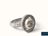 a close up of a ring with a pearl and diamonds on it