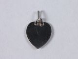 a close up of a black heart shaped charm on a white surface